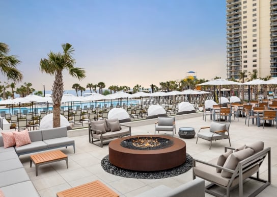 Black Drum exterior patio. Soft seating around a firepit.