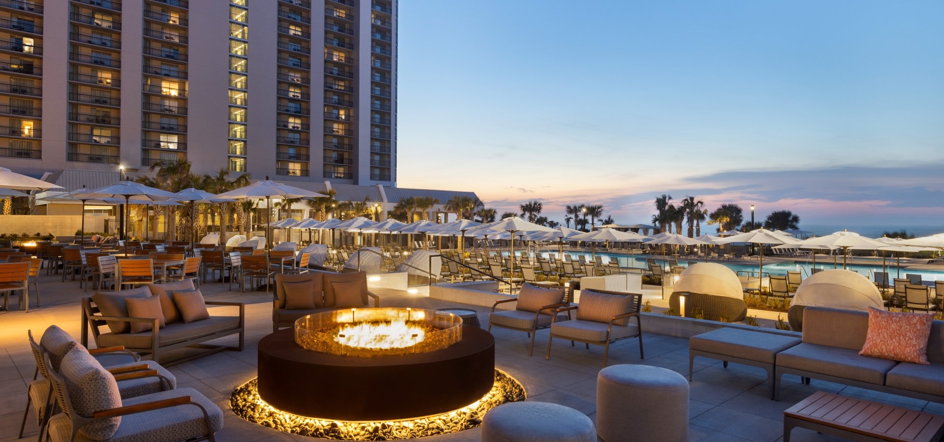 Black Drum Brewing patio with soft seating around the fireplace. It is dusk with pink and blue sky