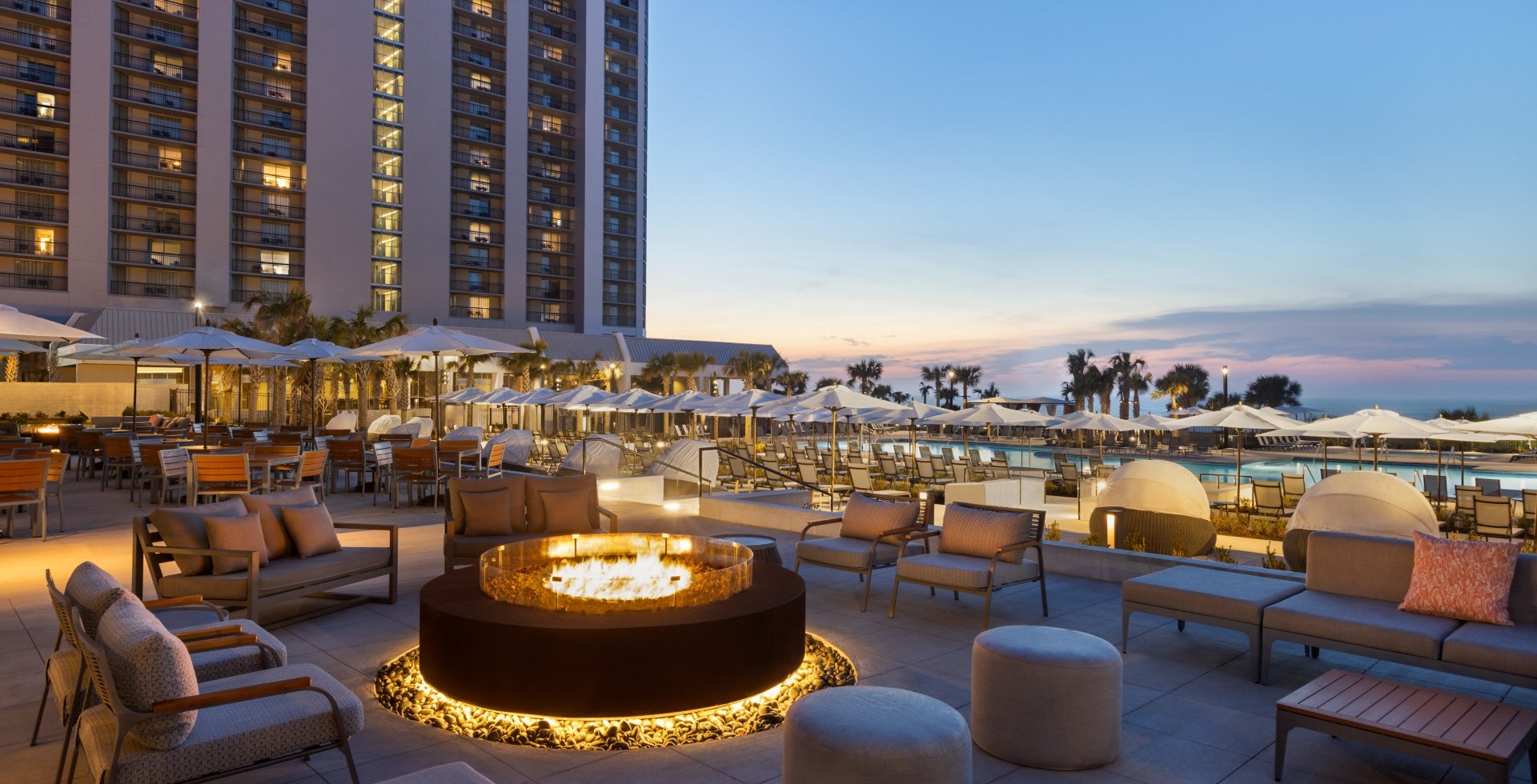 Black Drum Brewing patio with soft seating around the fireplace. It is dusk with pink and blue sky