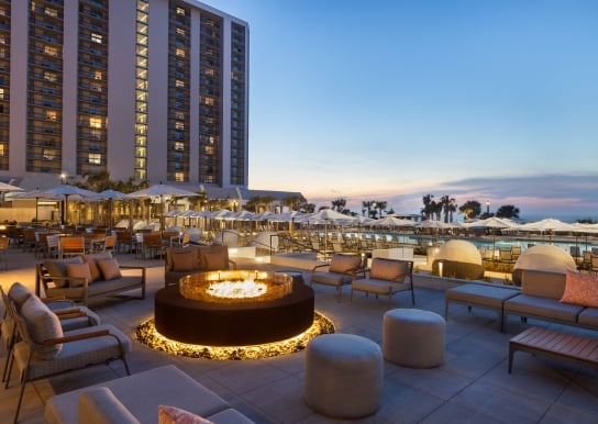 Black Drum Brewing patio with soft seating around the fireplace. It is dusk with pink and blue sky
