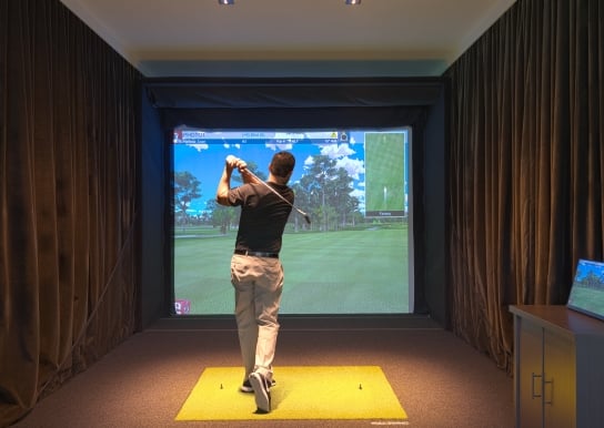 A guy using one of the golf simulators at 78Fitness