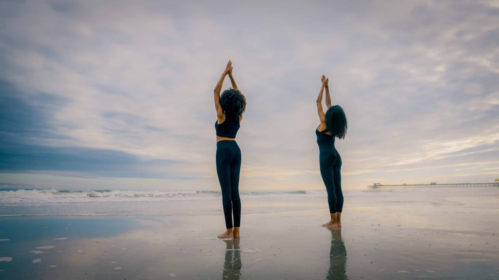 Two women doing yoga on the beach