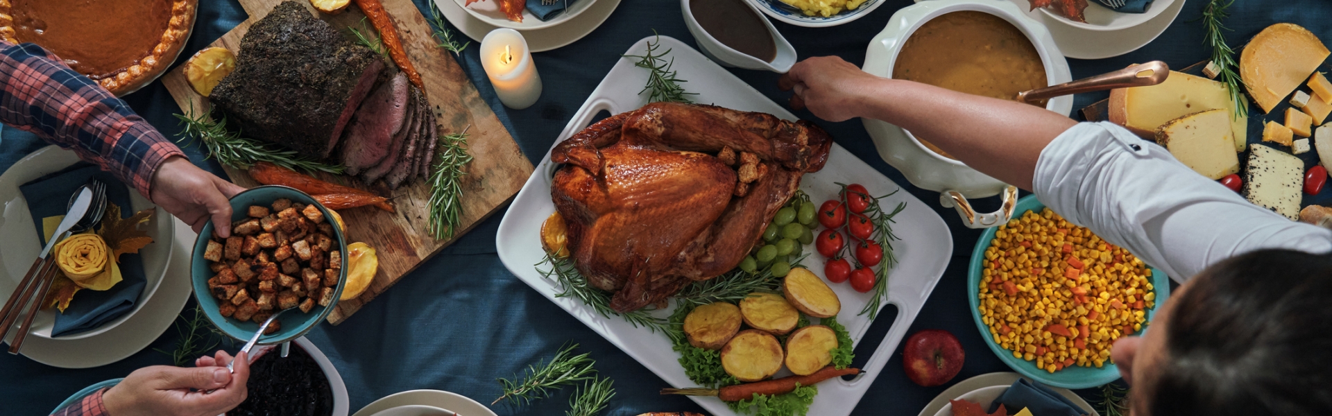 Thanksgiving feast spread out on a table with a family sitting around passing food
