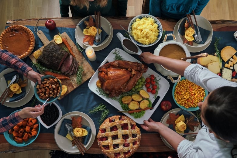 Thanksgiving feast spread out on a table with a family sitting around passing food