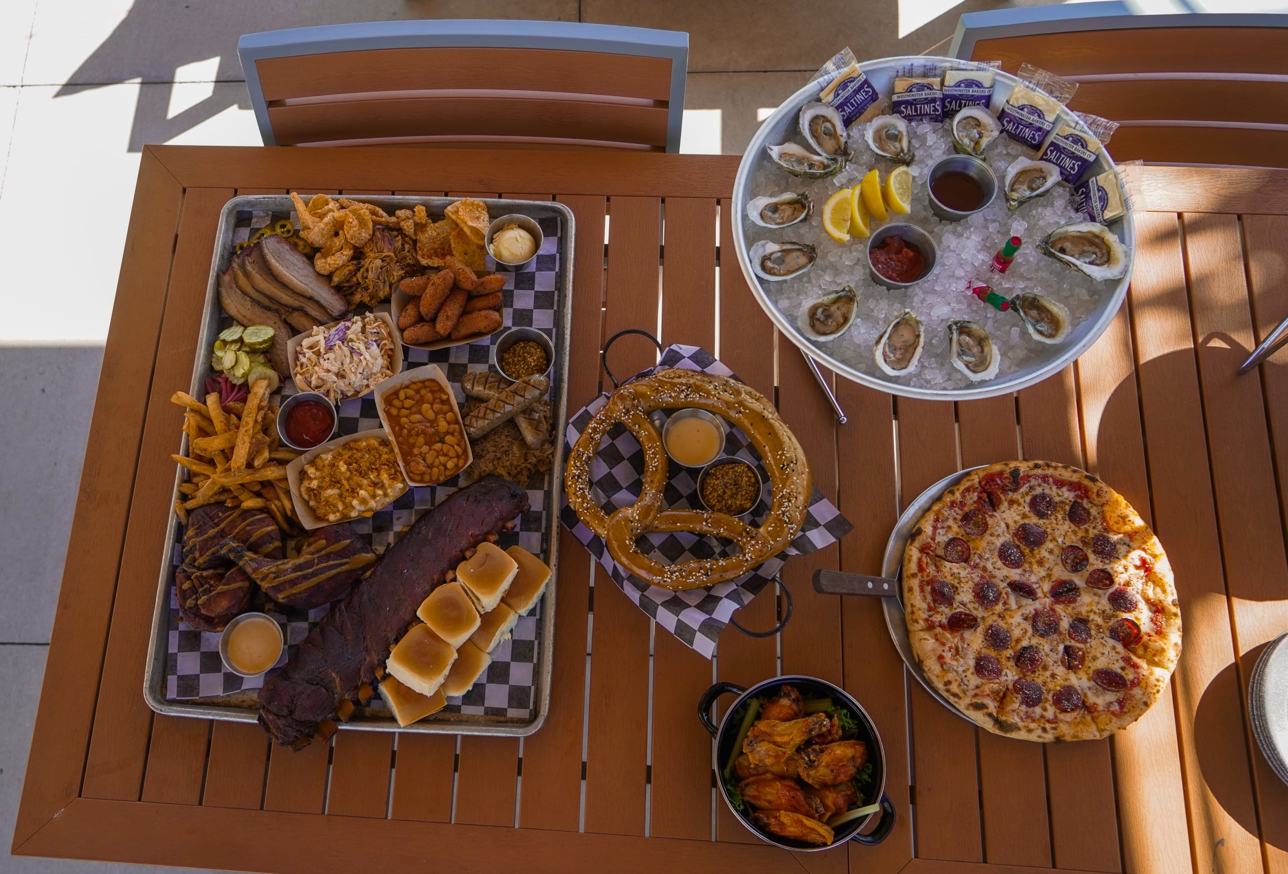 Black Drum Brewing BBQ Board, Bavarian Pretzel, Raw Oysters, Chicken Wings, and Pepperoni Pizza on a table