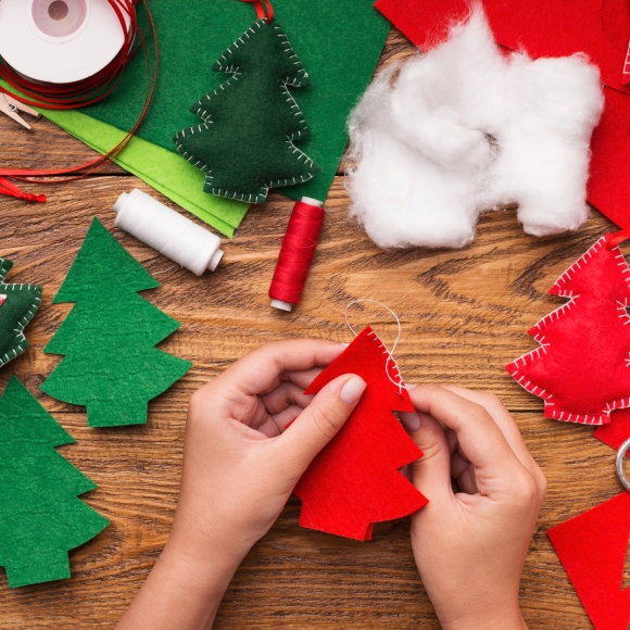 Someone hand crafting felt Christmas tree ornaments