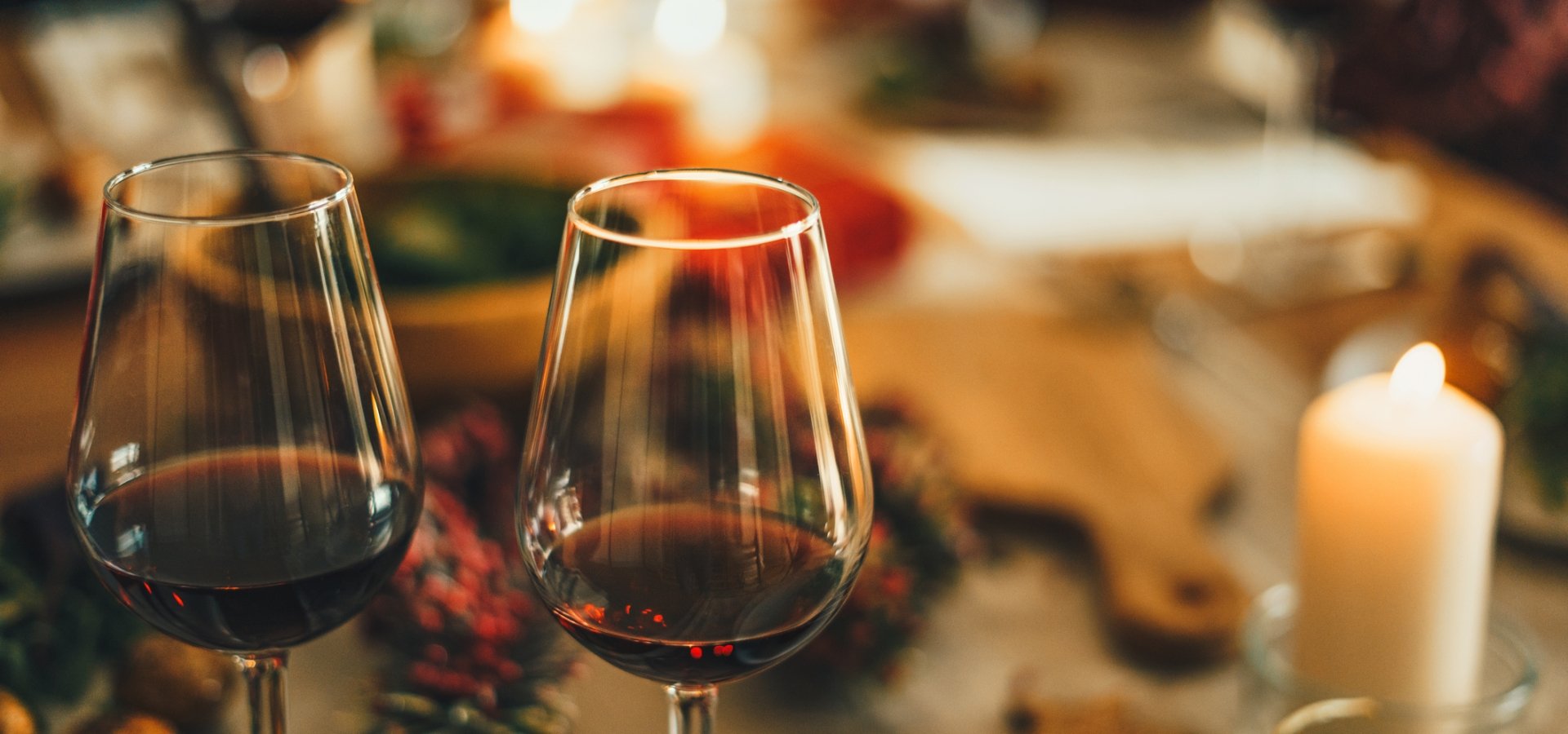 Two glasses of red wine overtop a blurred out Holiday meal spread