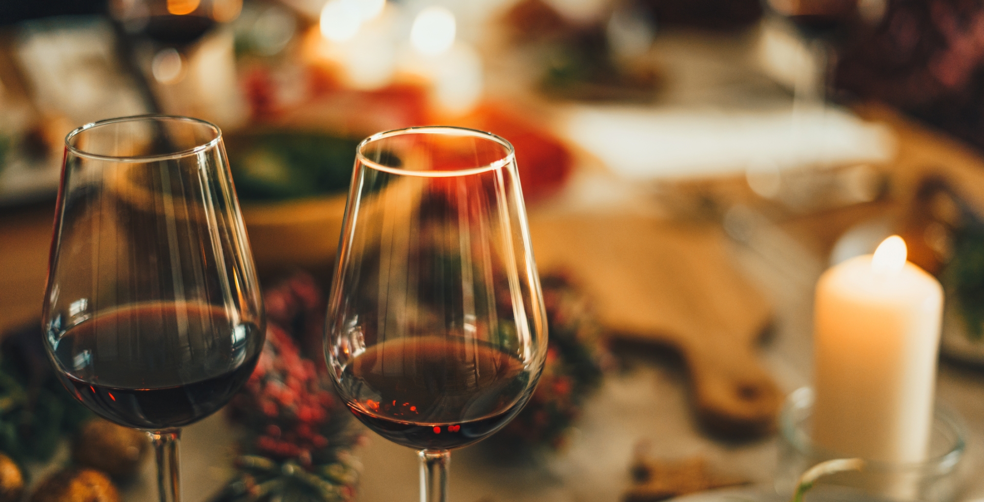 Two glasses of red wine overtop a blurred out Holiday meal spread