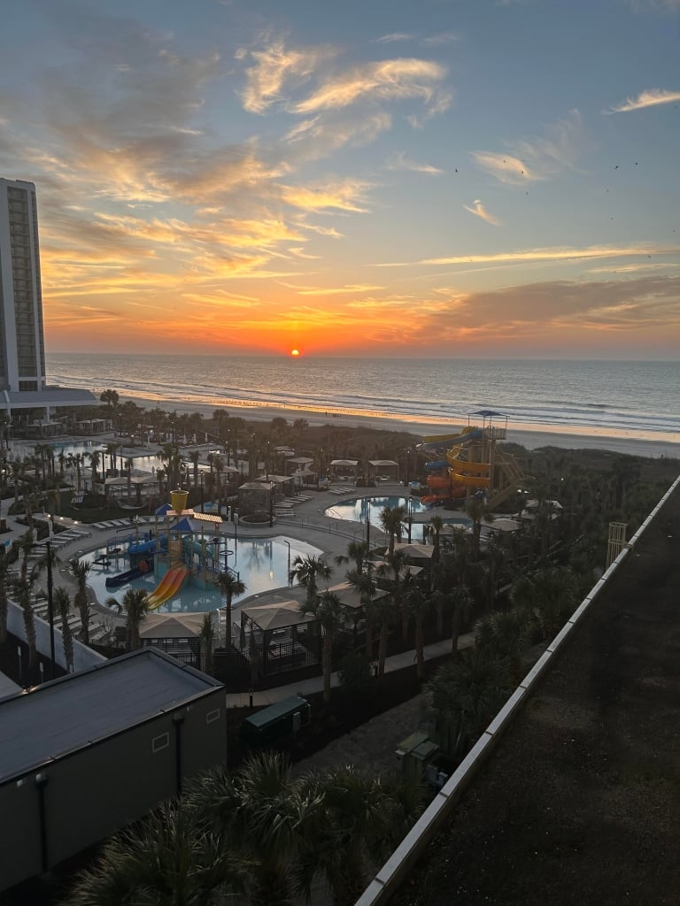 A sunrise view of a beach overlooking a waterpark.