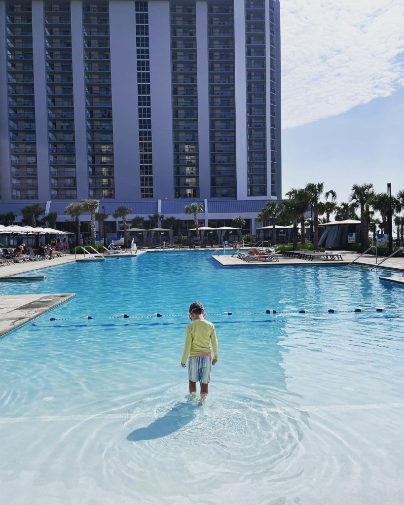 A small child walks into a zero entry pool.
