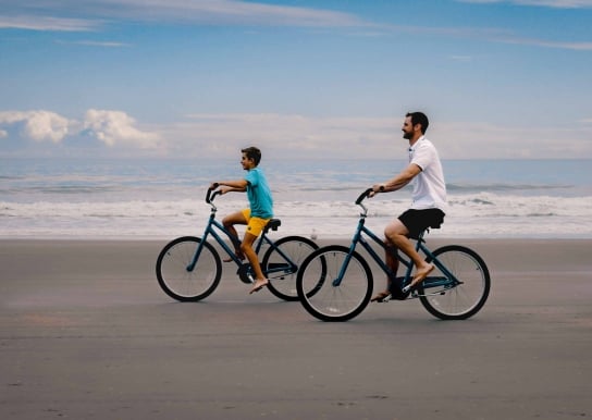 A father and Son biking on the beach