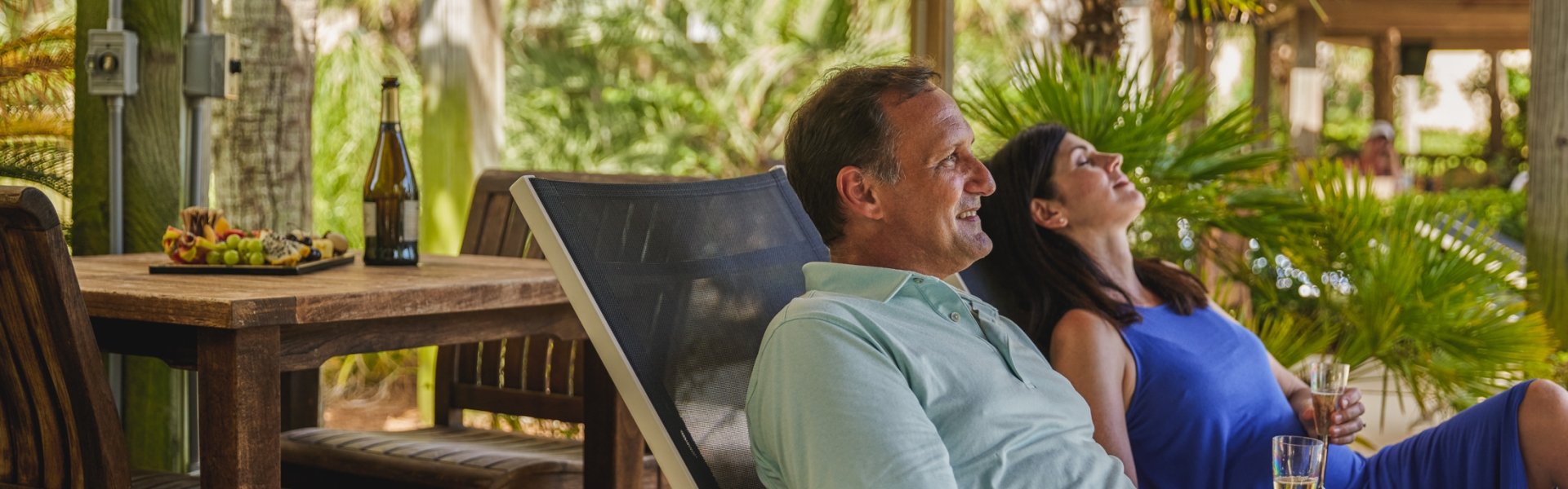 Couple enjoying their poolside cabana with wine and a fruit tray