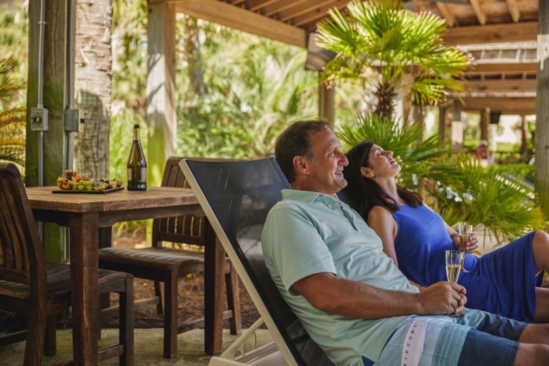 Couple enjoying their poolside cabana with wine and a fruit tray