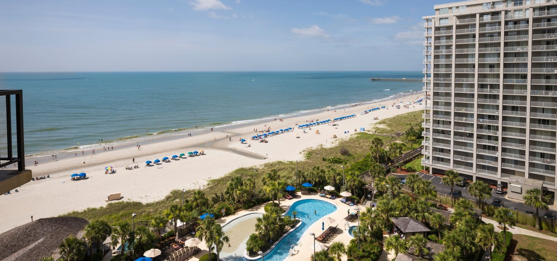 view of the ocean and sand bottom pool from a Hilton balcony