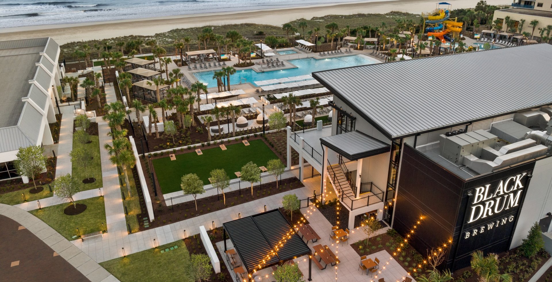 An aerial shot of a restaurant, pool, and beach in the background.