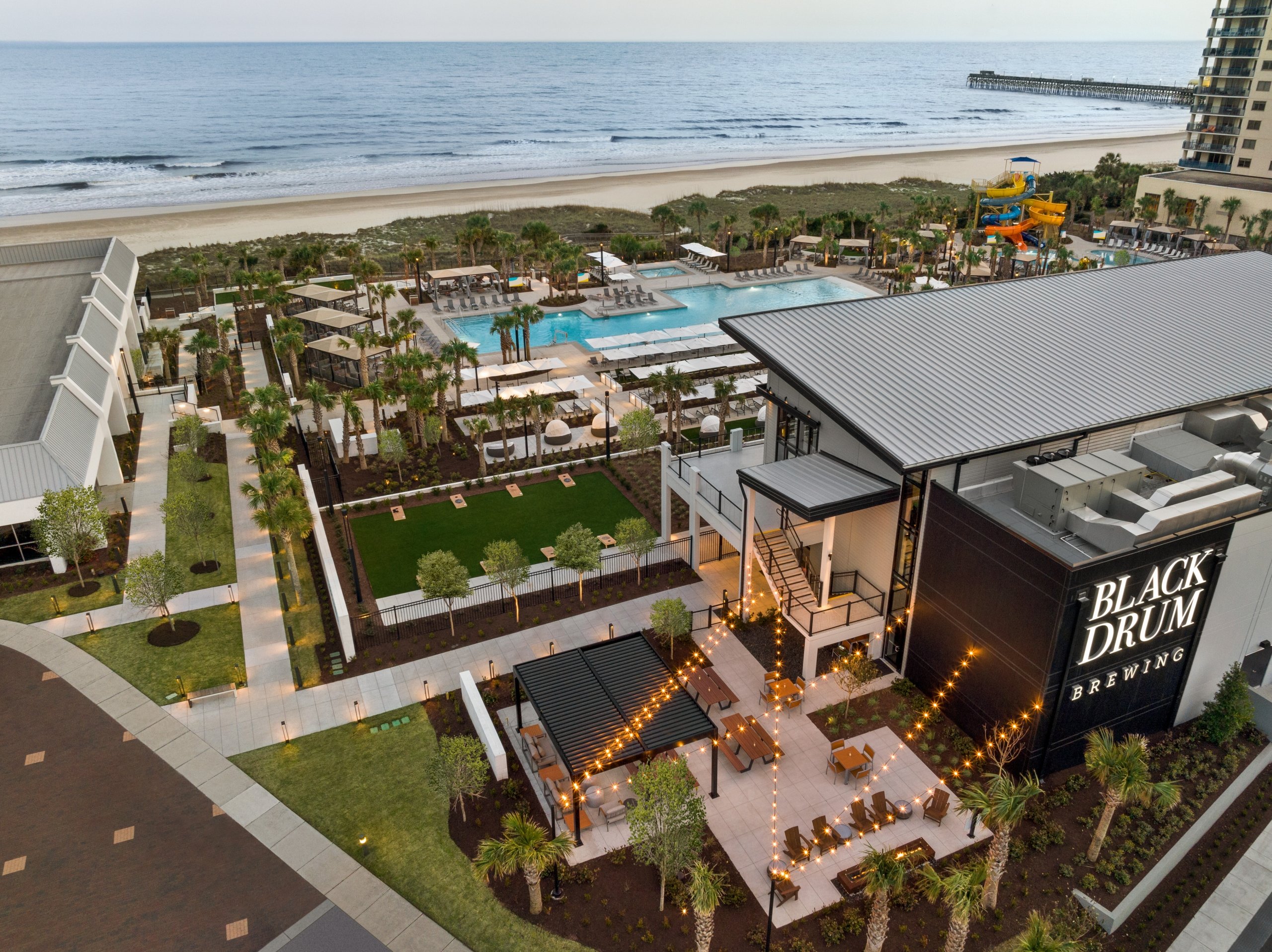 An aerial shot of a restaurant, pool, and beach in the background.