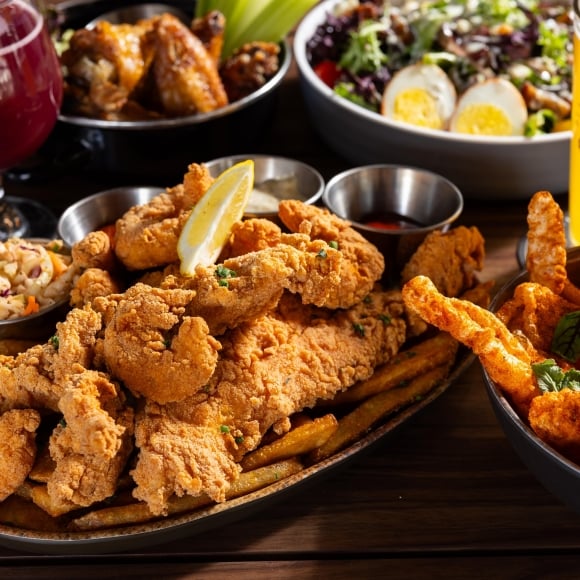 Black Drum Brewing spread of food including the shrimp & fish platter, pork skins, a cobb salad, wings, and beer