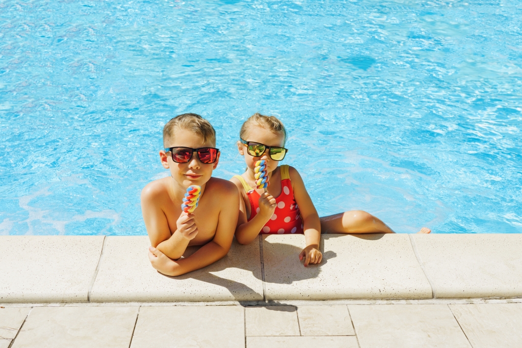 Happy siblings eating ice cream in a swimming pool