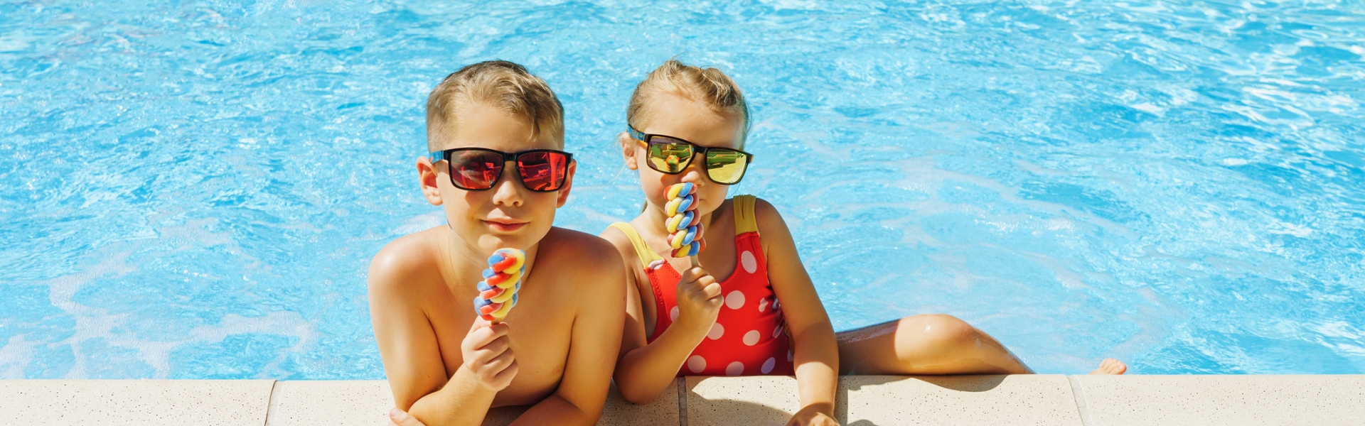 Happy siblings eating ice cream in a swimming pool
