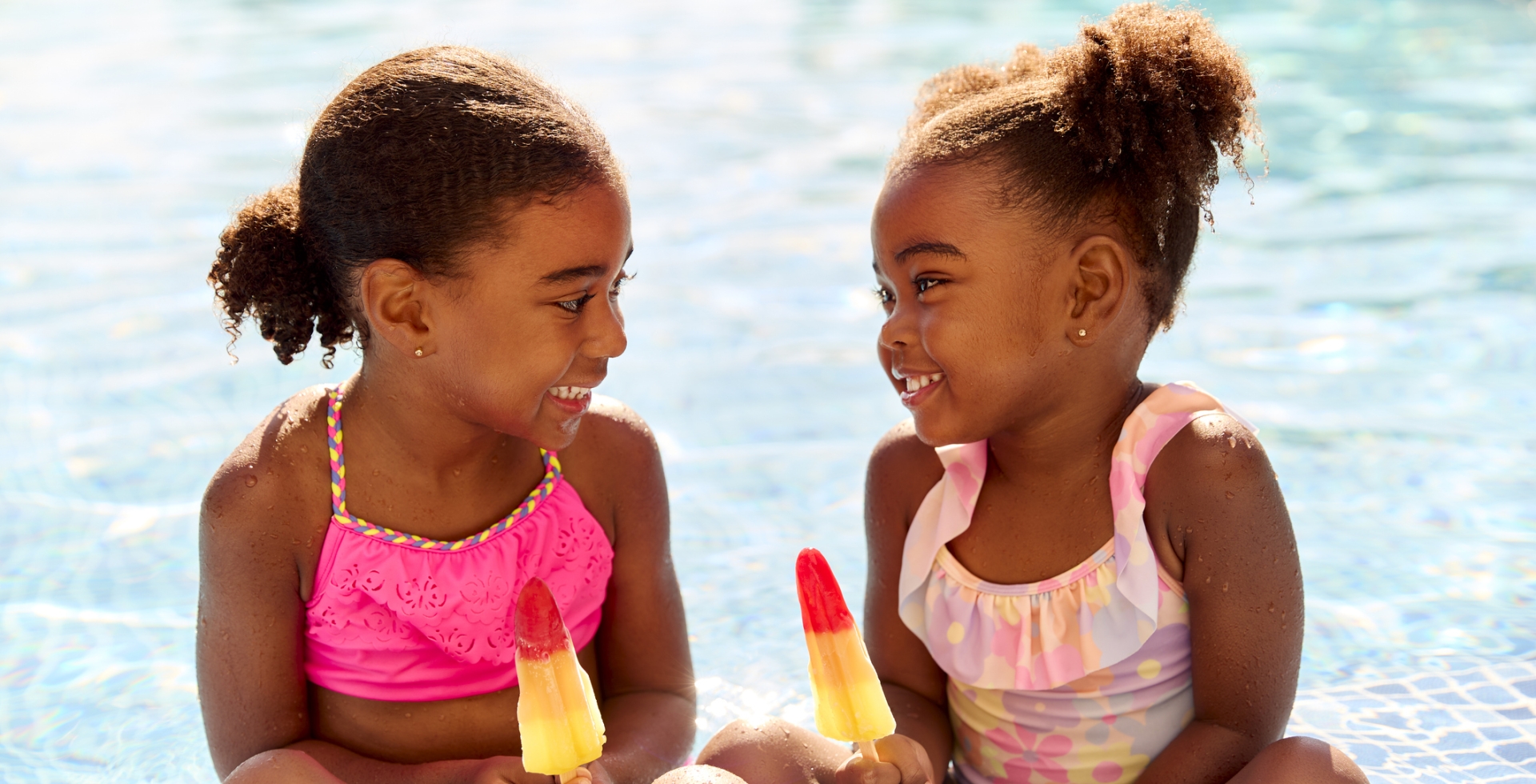 Two Girls Eating Ice Lollies in the Swimming Pool