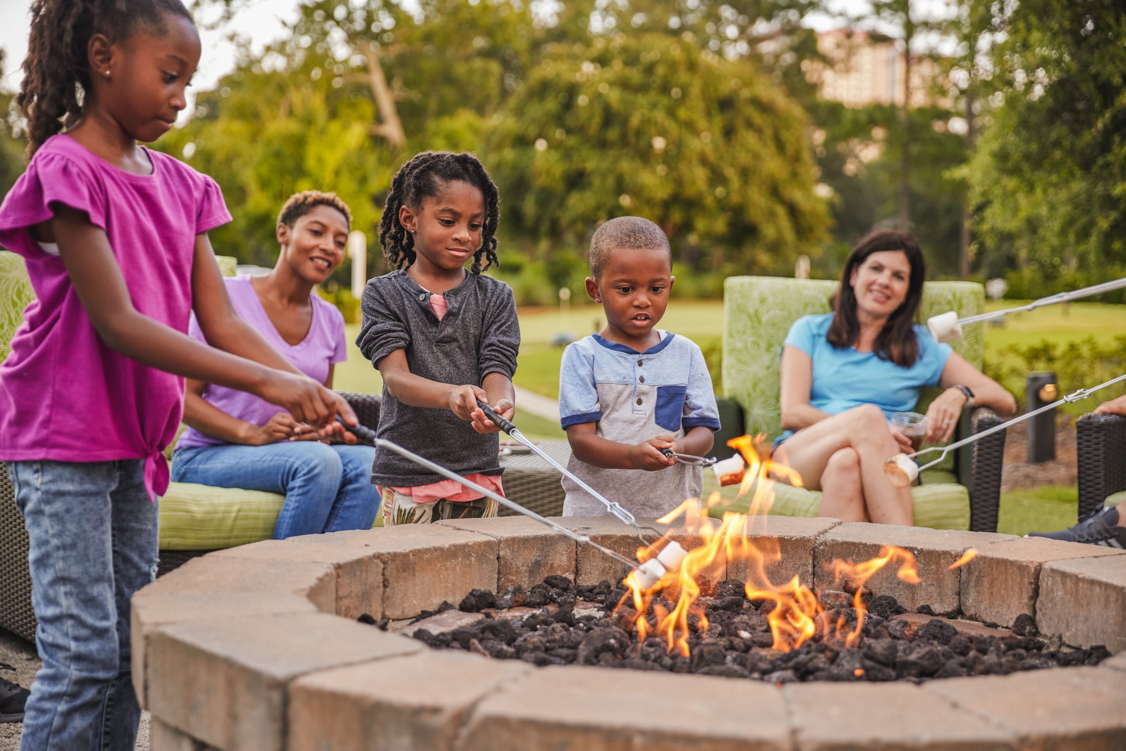 Families sitting around a firepit while the kids are roasting marshmallows