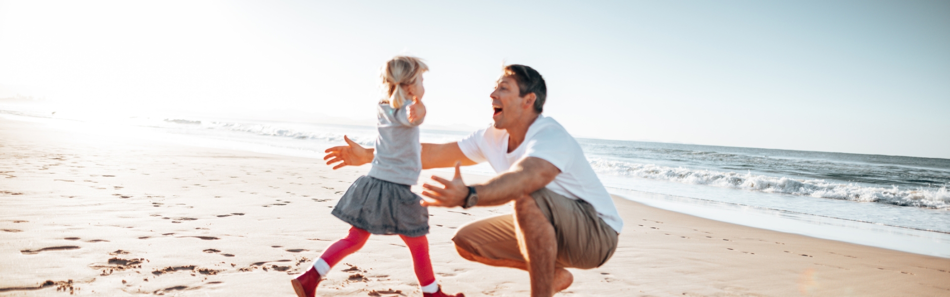 Daughter running into dads arms on the beach