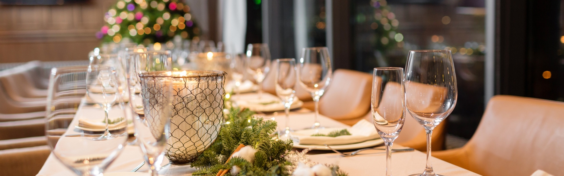 A long table set for a Christmas dinner with a Christmas tree in the background