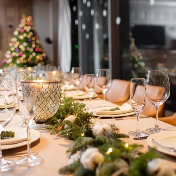 A long table set for a Christmas dinner with a Christmas tree in the background