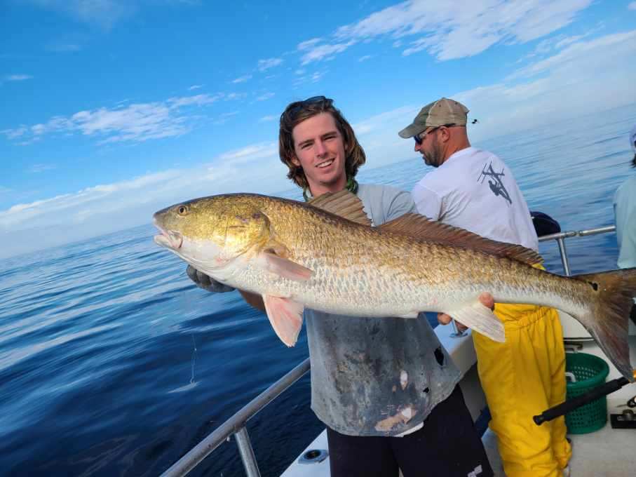 Boat Cruises with Little River Fishing Company - man holding a fish in the ocean
