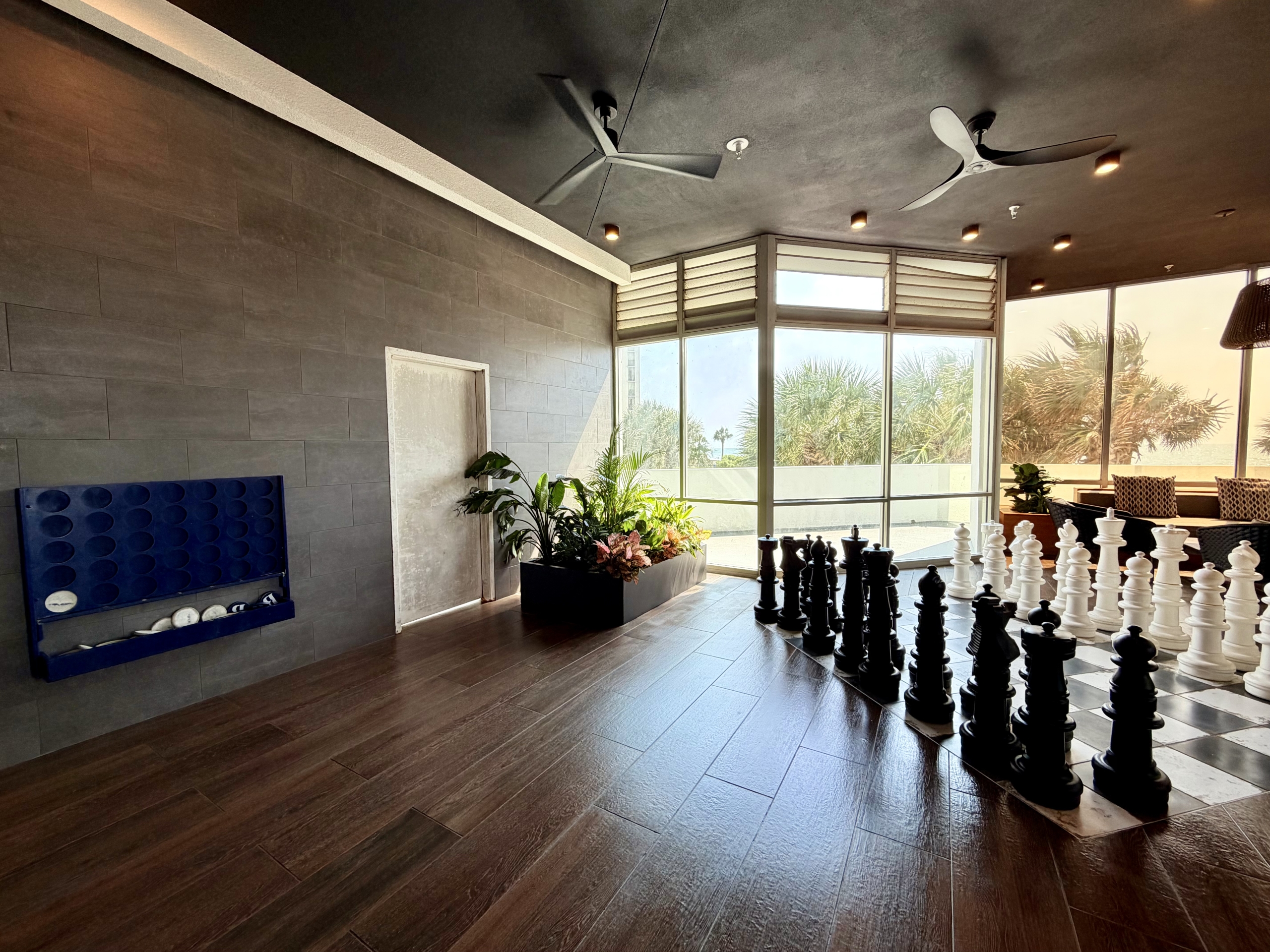 Hotel lobby lounge with oversized chess set by large windows and potted plants